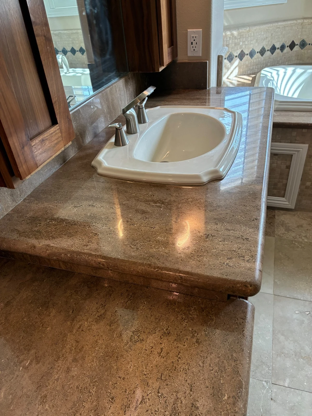The same vanity countertop after polishing, the faucet and light reflecting cleanly in the stone